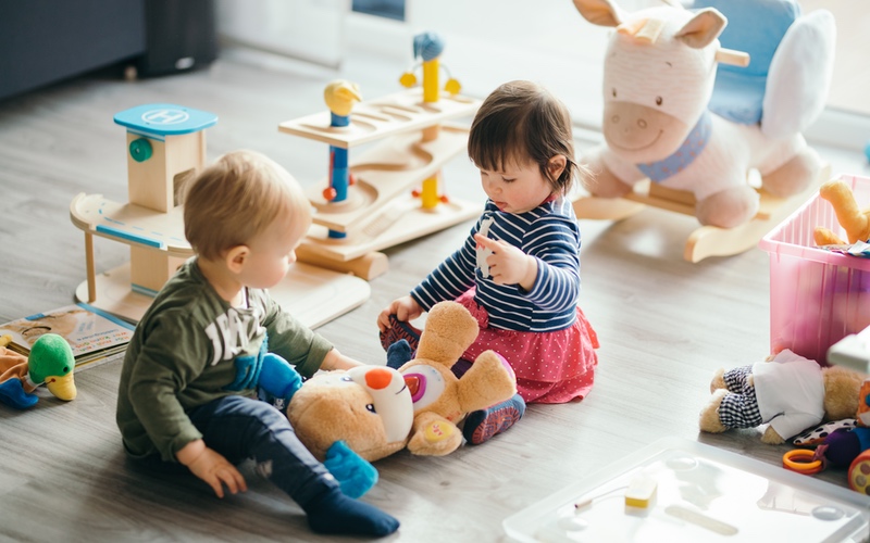 Two toddlers developing social skills by playing together with toys - tips from Romp n' Roll in Pittsburgh, PA.
