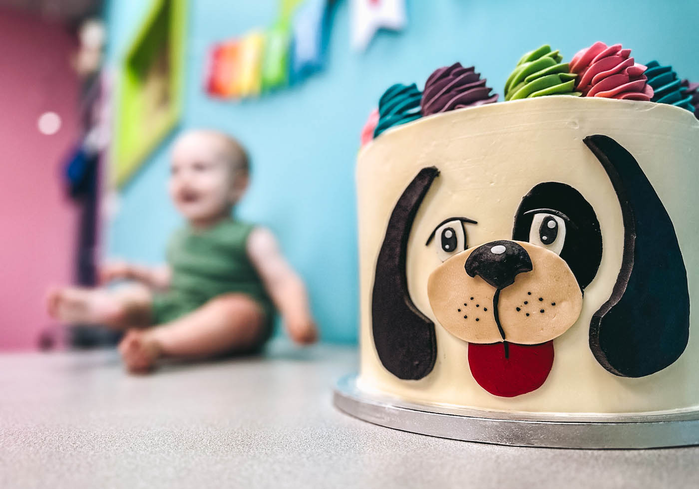 A baby sitting next to a Rompy birthday cake - contact Romp n' Roll today to discuss birthday party franchise opportunities.