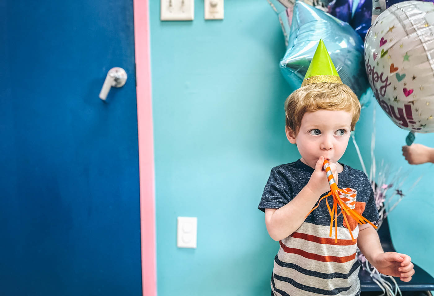 A kid with a party hat and horn at Romp n' Roll - a kids party franchise!