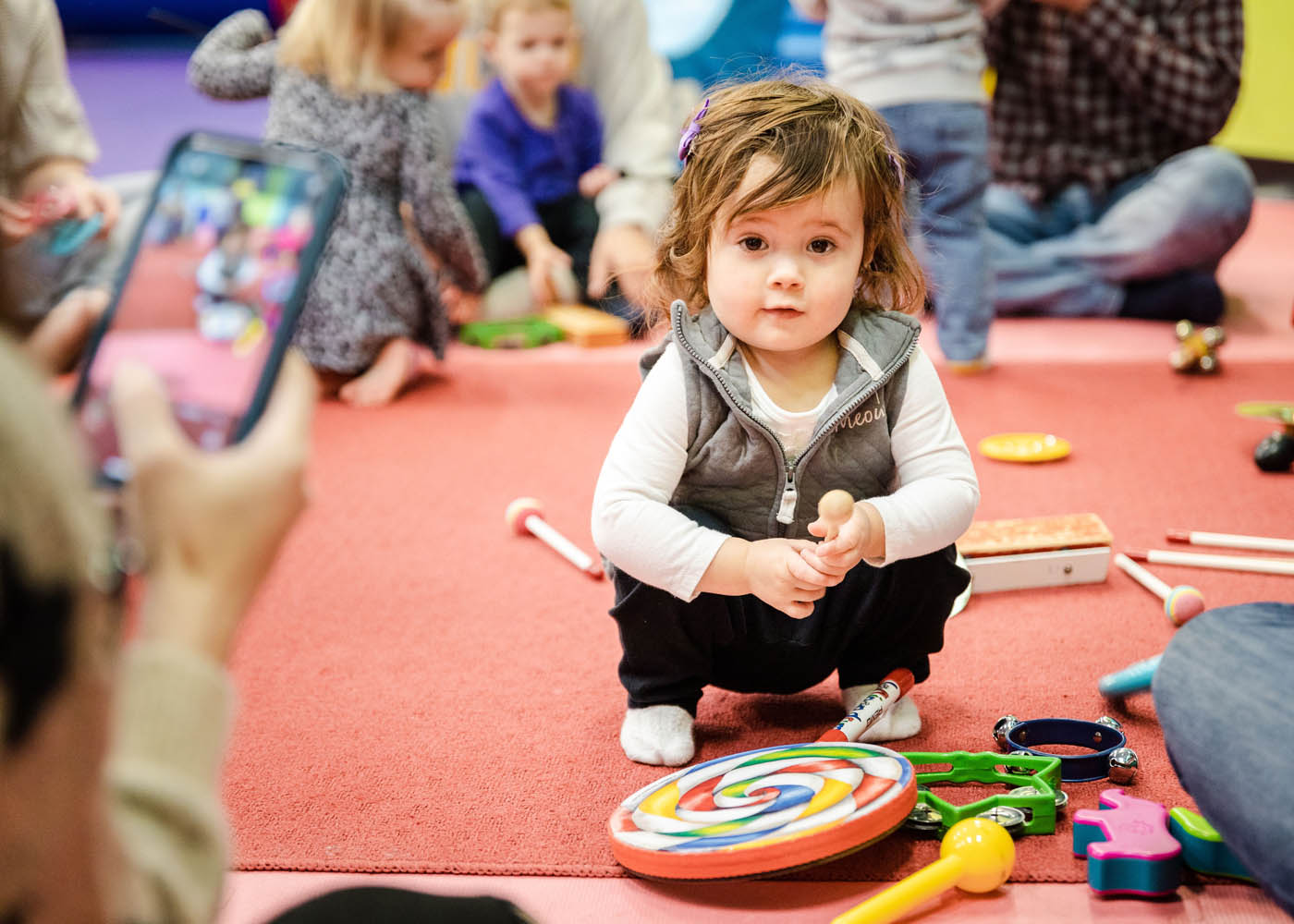 An adorable little girl sitting in front of musical instruments at a Romp n' Roll in Midlothian baby music class.