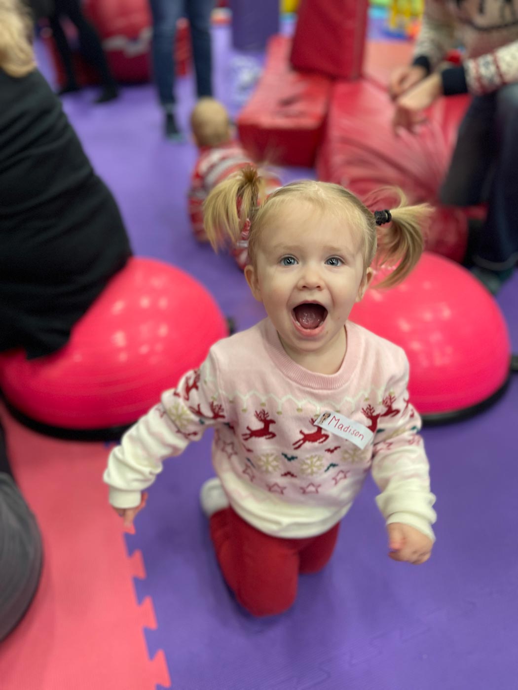 A little girl on a purple matt, having fun at Romp n' Roll's winter camp in Pittsburgh, PA. 