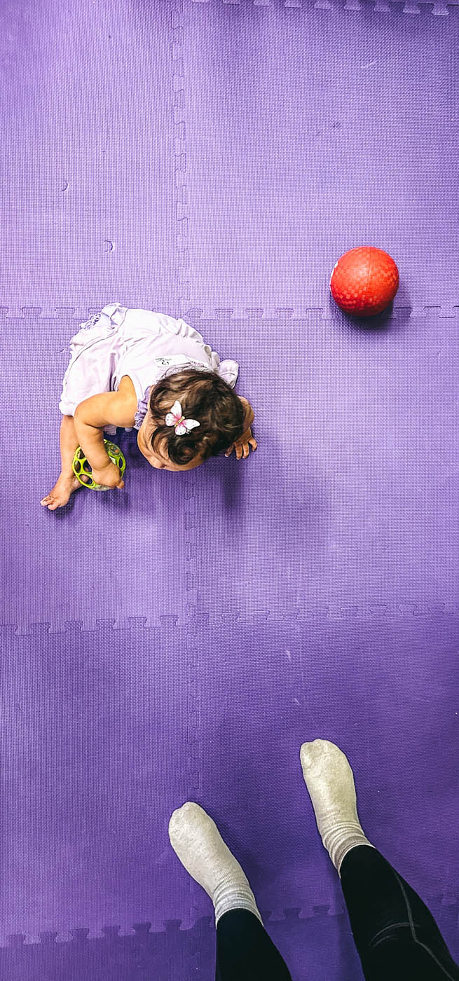 An image of a girl next to a red ball against a purple floor - book with Romp n' Roll Charlotte today!