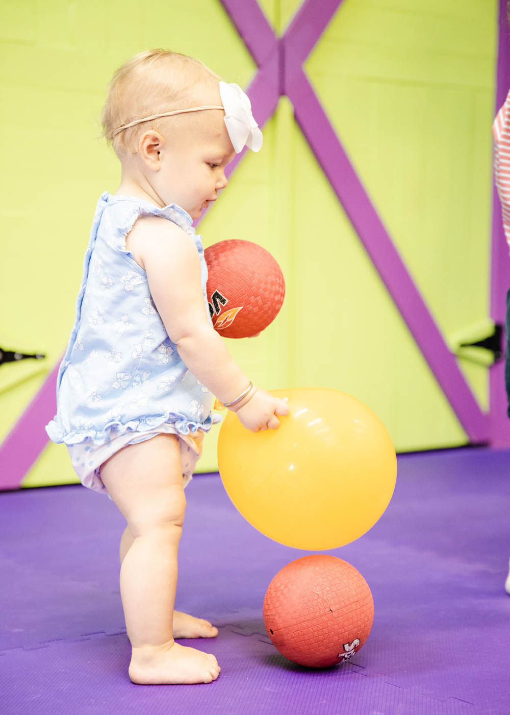 A very little child playing with balls and kid safe equipment in a sports class for 2 year olds in Glen Allen, VA with Romp n' Roll.