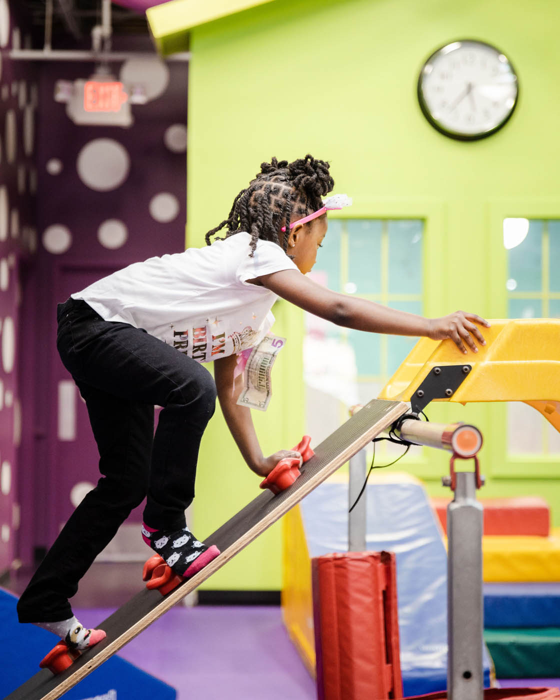 A girl climbing on kid-safe gym equipment at a Raleigh toddler tumbling class. 