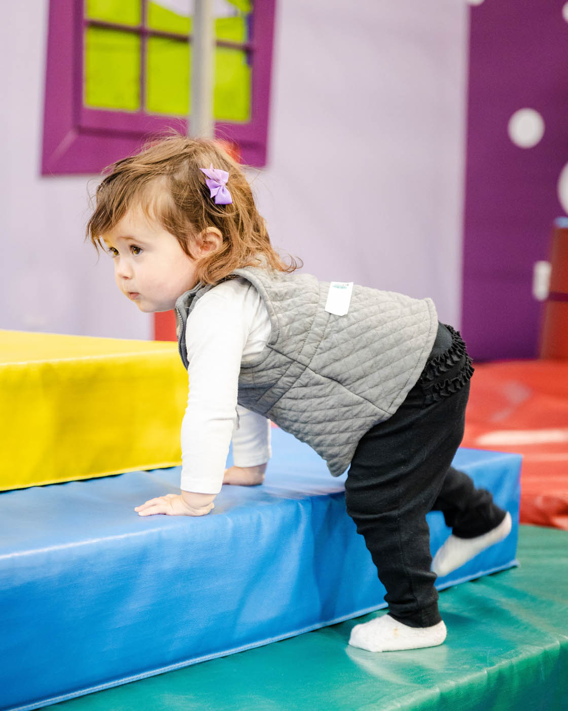 A little girl climbing on soft tumbling equipment for toddlers at Romp n' Roll in Willow Grove, PA.
