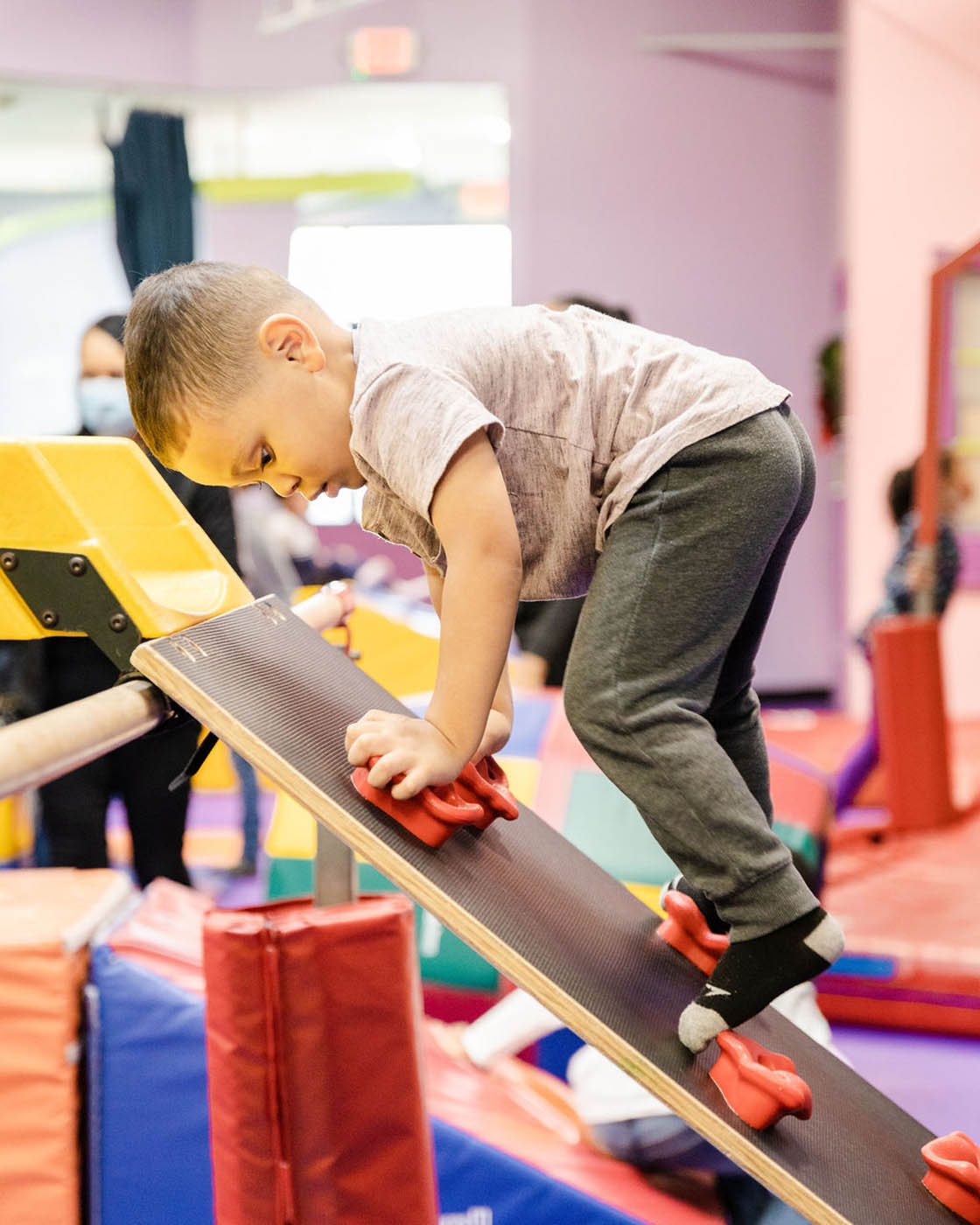 A young boy using a small climbing wall in Romp n' Roll's gym class in Pittsburgh.
