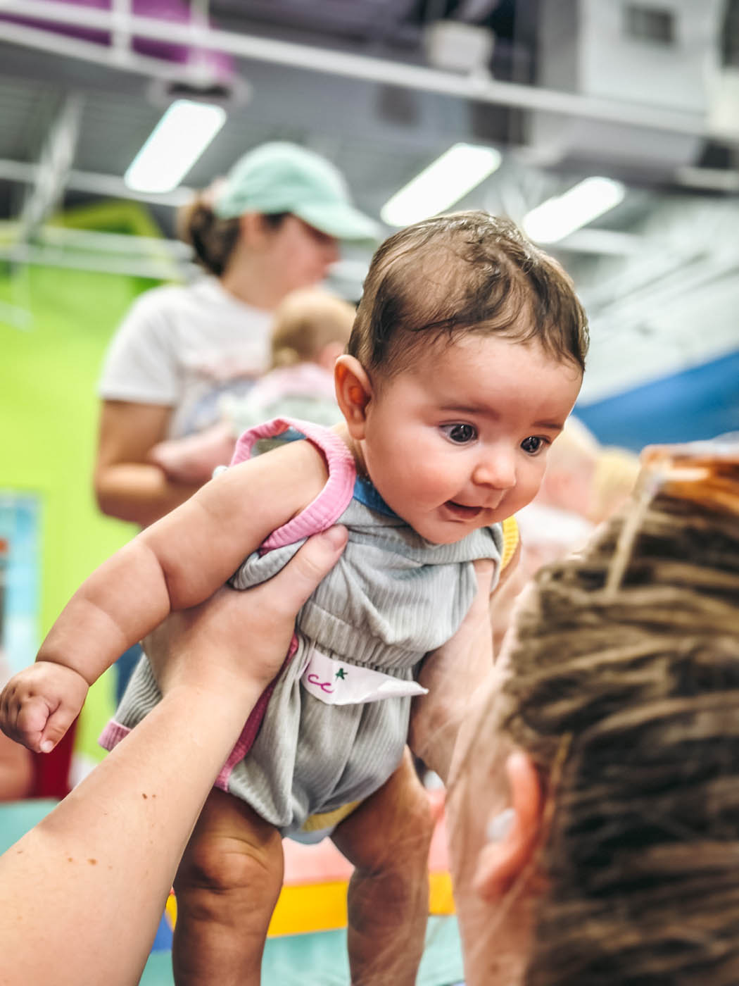 A baby being held in the air at Romp n' Roll Willow Grove's classes for babies in Willow Grove, PA