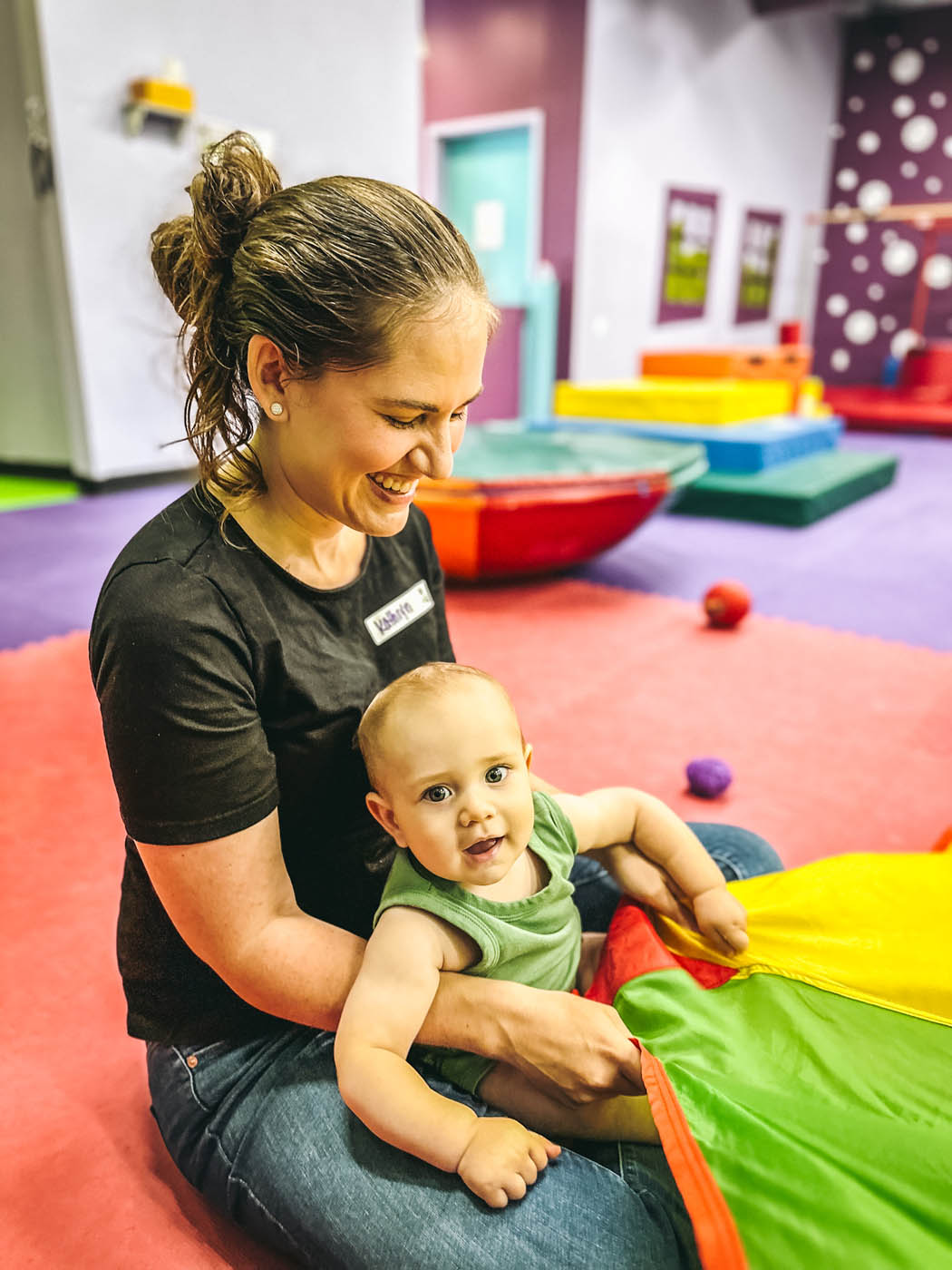 A baby having parachute fun with a Romp n' Roll instructor at our baby activities in Charlotte, NC.