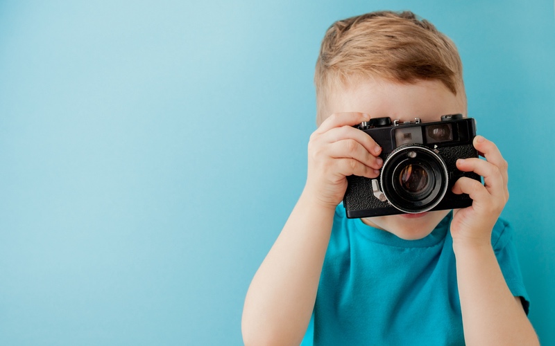 Young child holding a camera up to take a picture.