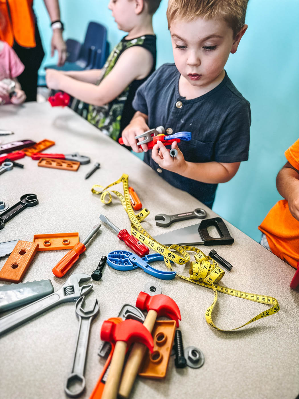 A child fascinated by tools while attending a Romp n' Roll class.