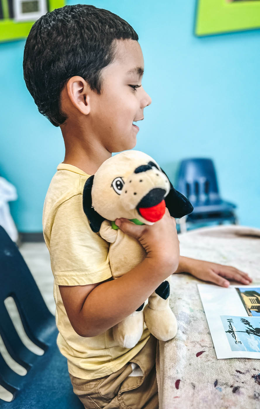 A little boy holding a stuffed animal rompy at a parents morning out event.