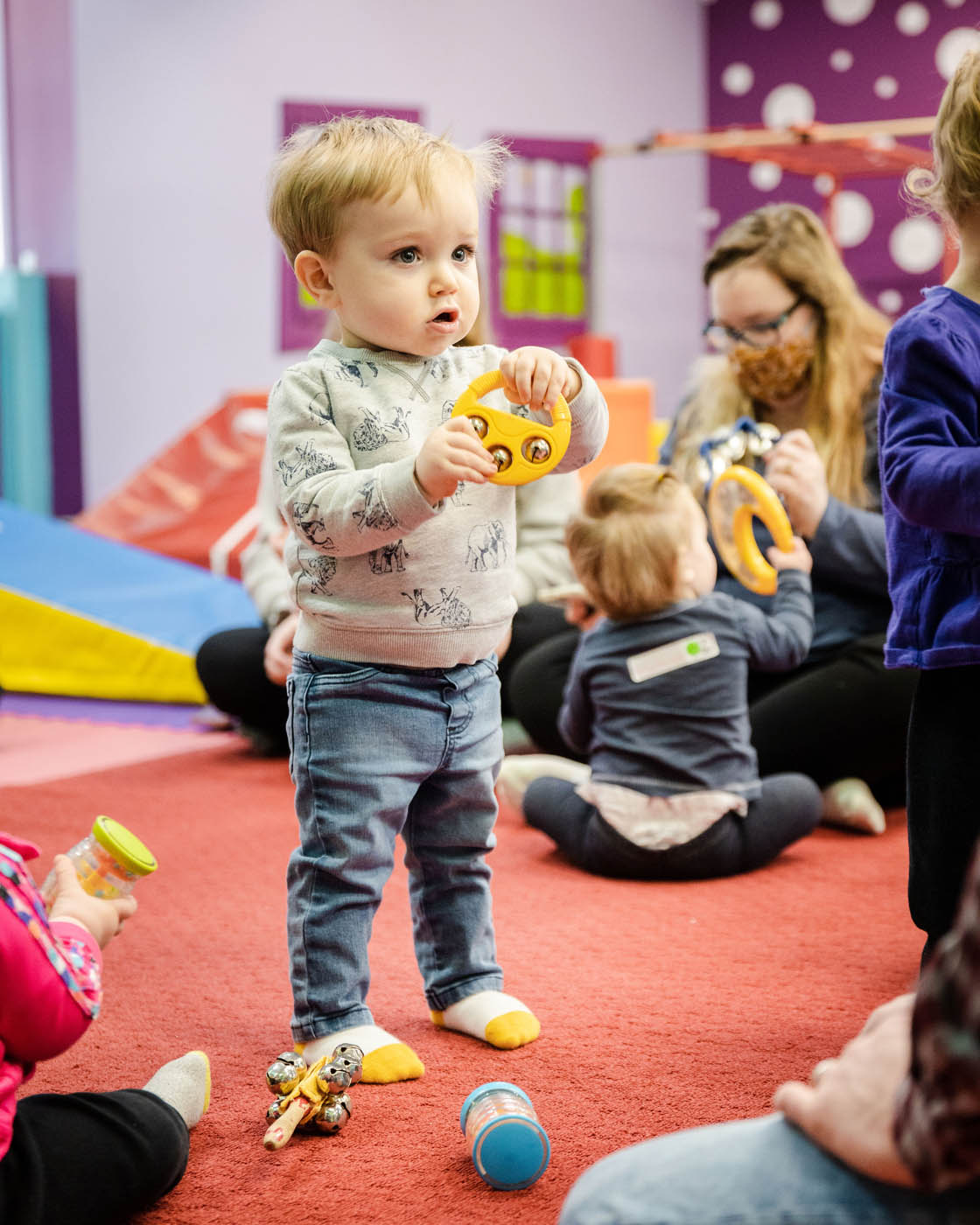 A young boy holding a musical instrument at a toddler music class.