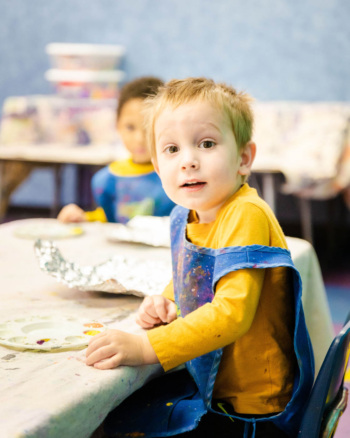A boy in a yellow shirt in a Katy toddler art class at Romp n' Roll.