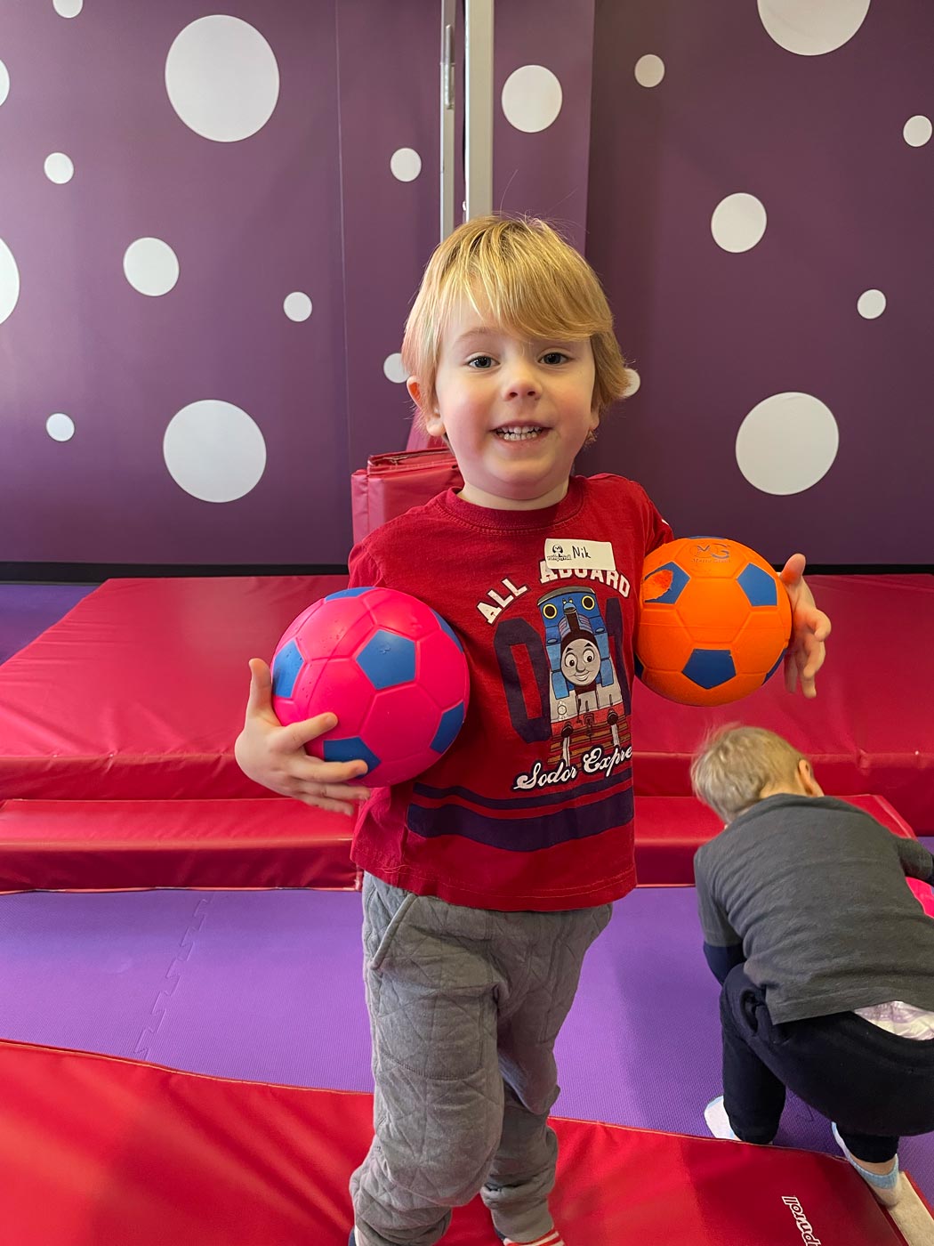 A boy playing with soccer balls in Romp n' Roll North Raleigh's gym.