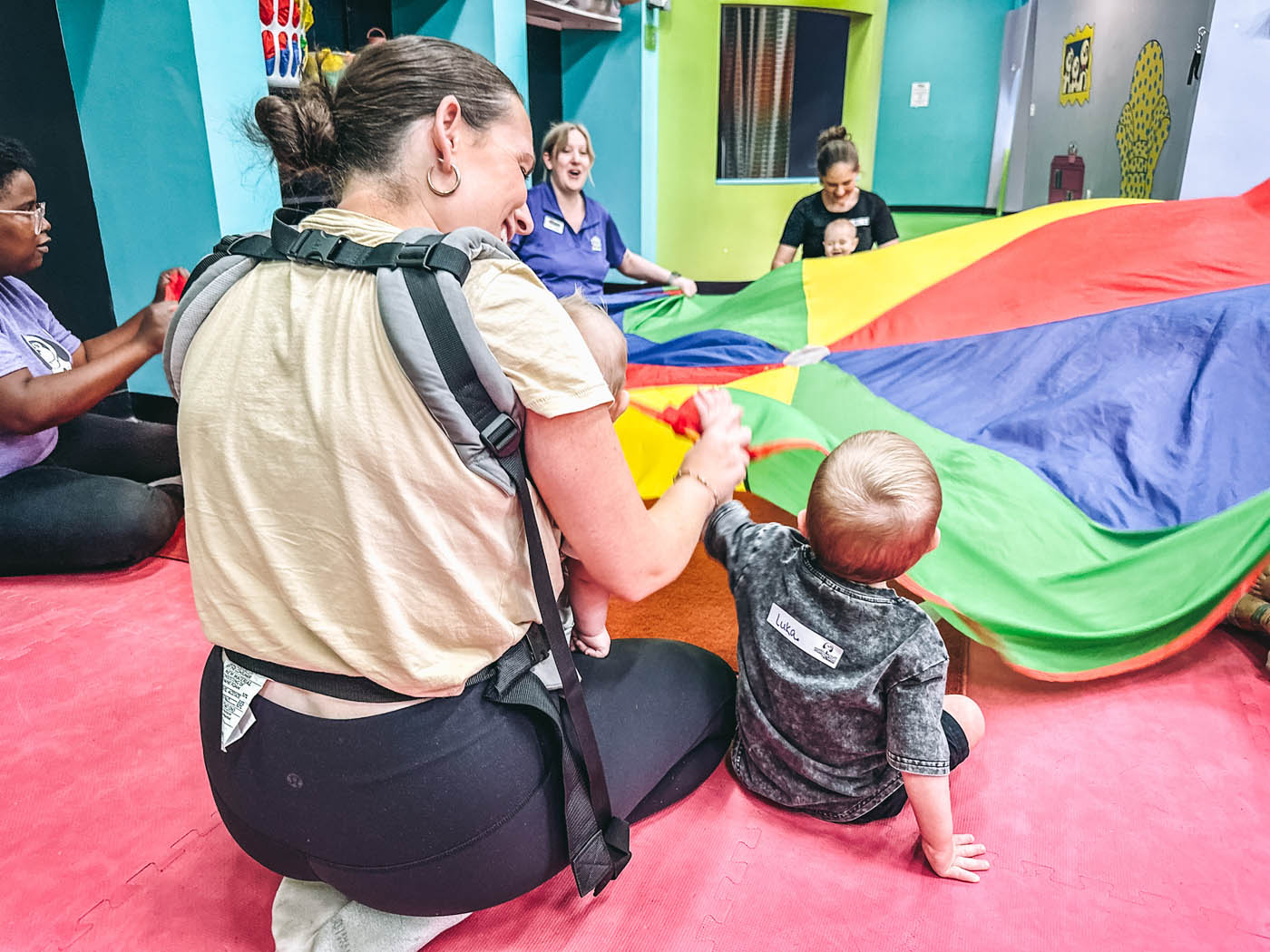 A Romp n' Roll instructor siting with a child at a kids gym franchise class.